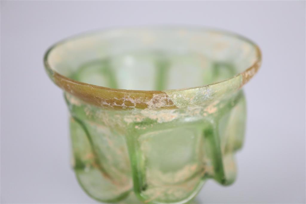 A Roman green glass auricular cup, 2nd/3rd century AD, 7.5cm high